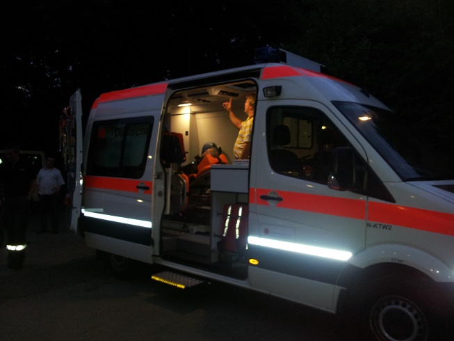 Blick von der Seite in den Krankentransportwagen. Hier liegt Peter Falk auf der Bahre