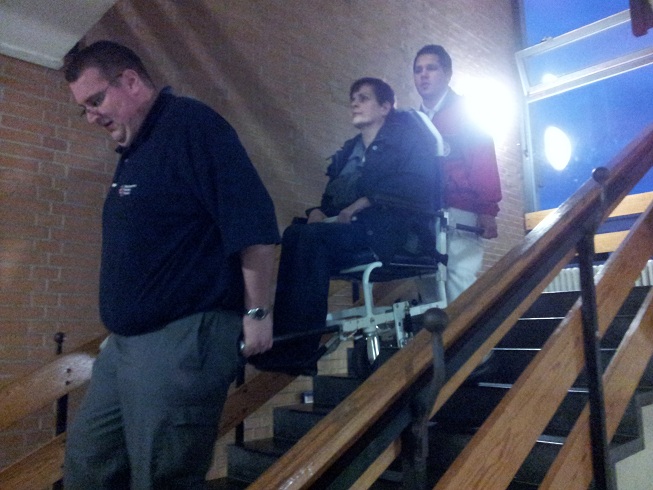 Zwei Rettungshelfer tragen Frau Giesen eine Treppe herunter