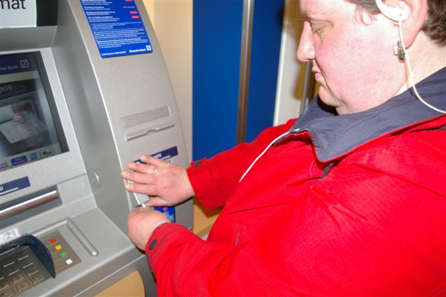 Frau St. Mont vor dem Geldautomaten der Deutschen Bank